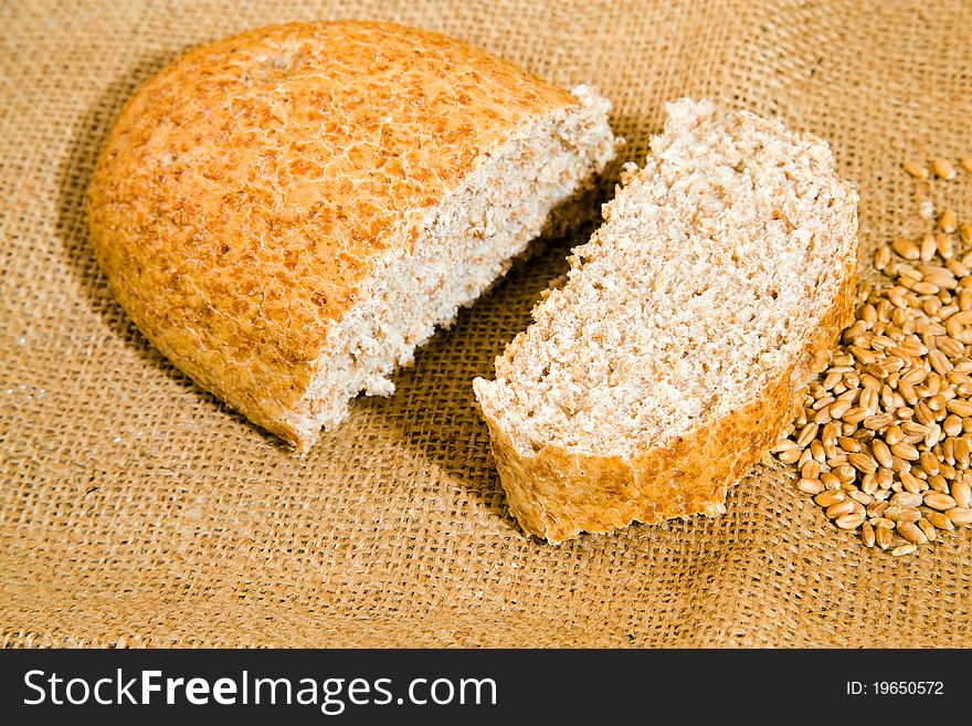 The loaf of bread lying together with wheat on a linen cloth. The loaf of bread lying together with wheat on a linen cloth