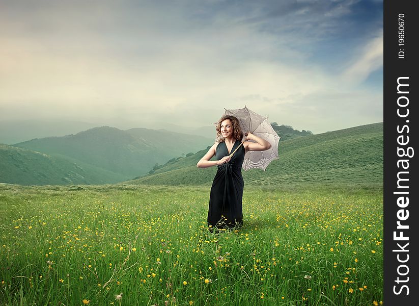 Beautiful woman holding an umbrella on a green meadow. Beautiful woman holding an umbrella on a green meadow