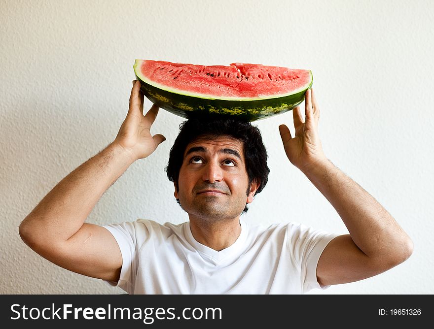 Man holding a watermelon on his head and looking up
