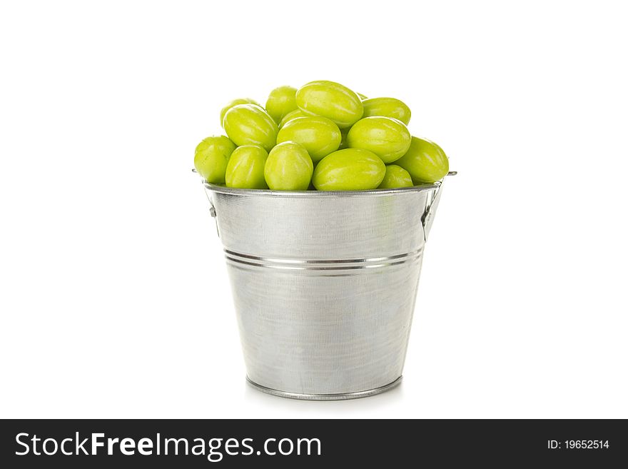 Many green candies in a steel bucket. Isolated on white background. Many green candies in a steel bucket. Isolated on white background