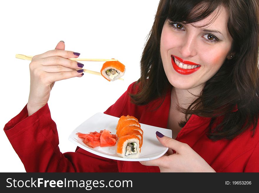 Close up of the plate with two rolled salmon with conger, cucumber and ginger and two chopsticks with roll in the woman's hand. Close up of the plate with two rolled salmon with conger, cucumber and ginger and two chopsticks with roll in the woman's hand..