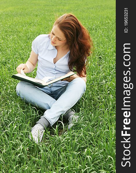 Girl sitting in the field and read the book