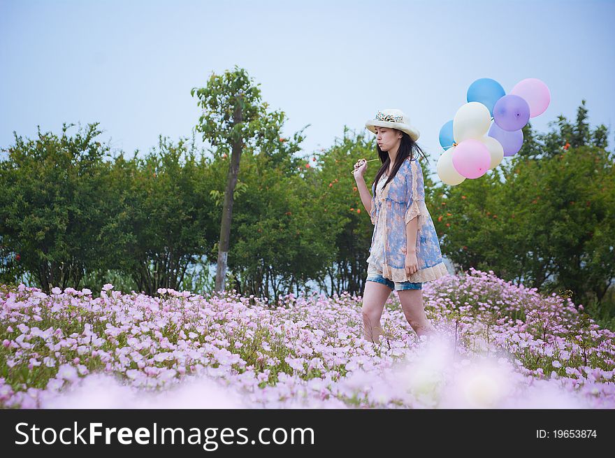 A girl in field with balloons in hand