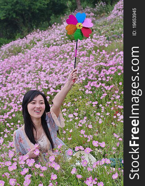 A girl in field with pinwheel in hand and flowers around