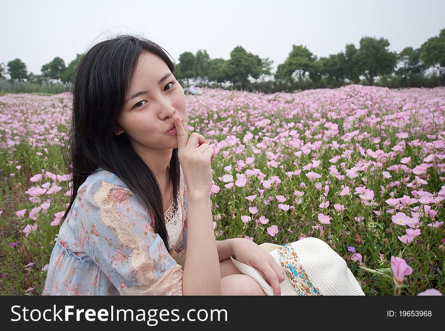 A girl doing silence gesture in field with flowers around. A girl doing silence gesture in field with flowers around