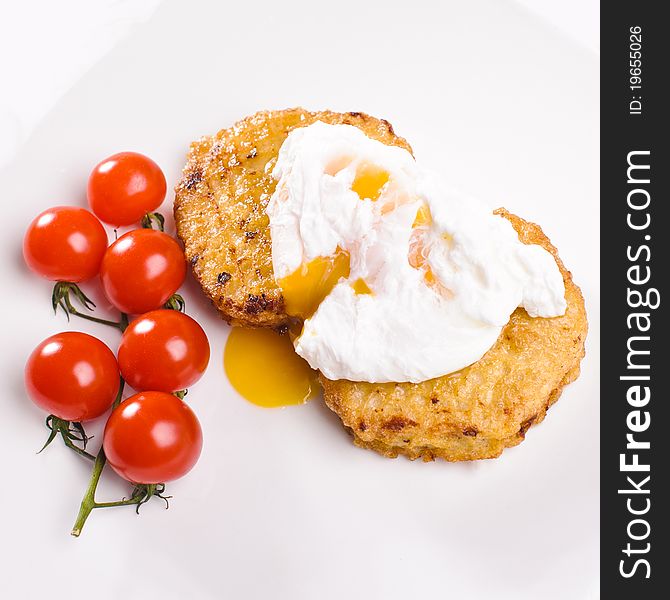Two cutlets with branch of small tomatos and egg on white plate
