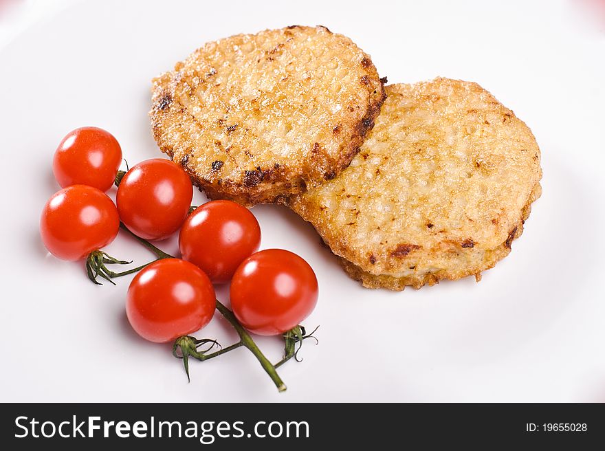 Two cutlets with branch of small tomatos on white plate