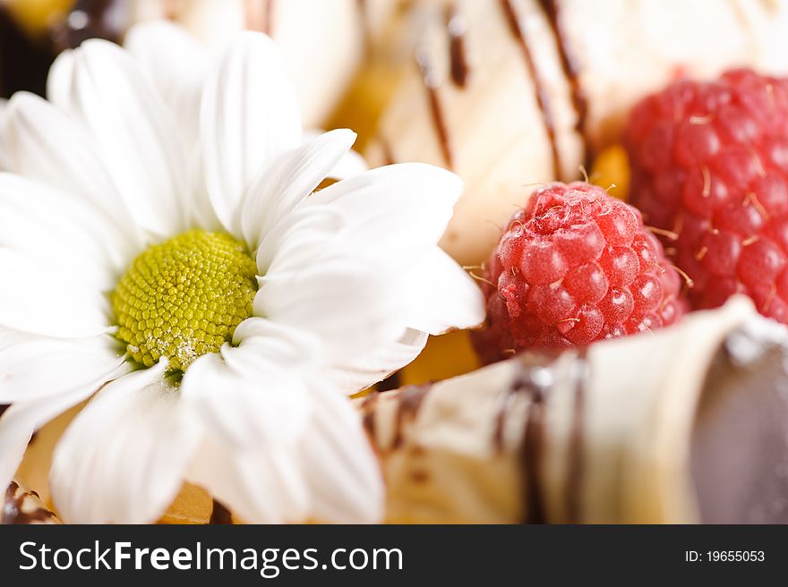 Piece of cake on plate with berries and fruits and camomile