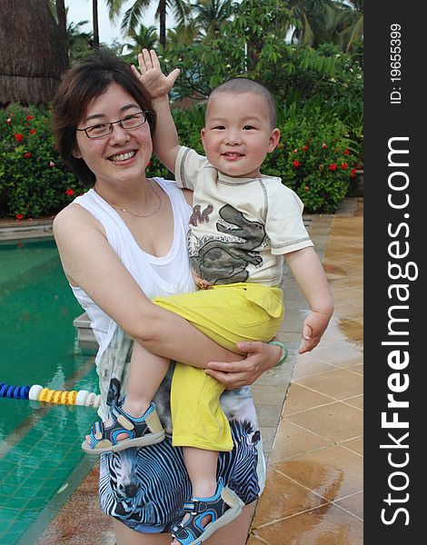 Young chinese mother with cute baby by the swimming pool. Young chinese mother with cute baby by the swimming pool