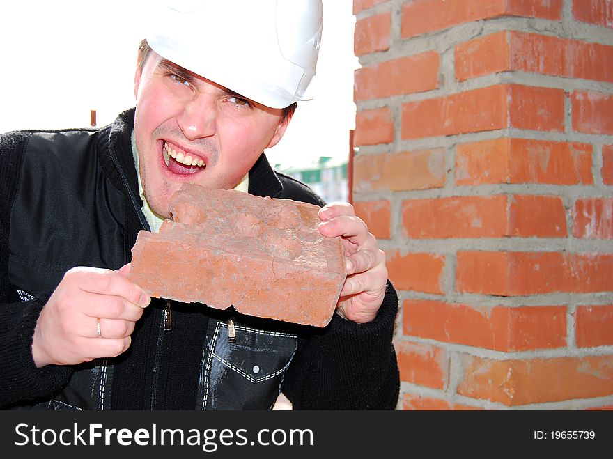 Young bricklayer in the helmet with brick. Young bricklayer in the helmet with brick.