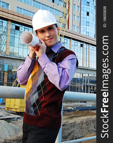 Industrial theme: architect, on a workplace, in a warm winter jacket and a helmet, has control over a tablet. Industrial theme: architect, on a workplace, in a warm winter jacket and a helmet, has control over a tablet.