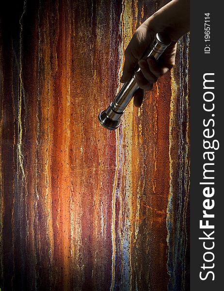 Hand holding a flashlight on rusty background