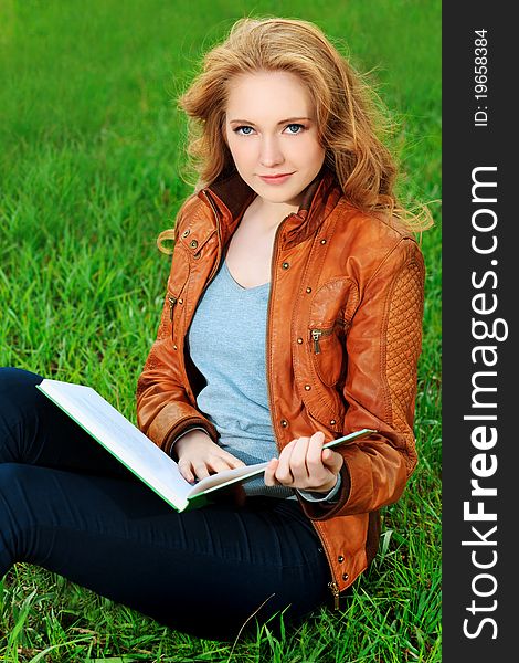 Beautiful smiling young woman reading a book outdoors. Beautiful smiling young woman reading a book outdoors.