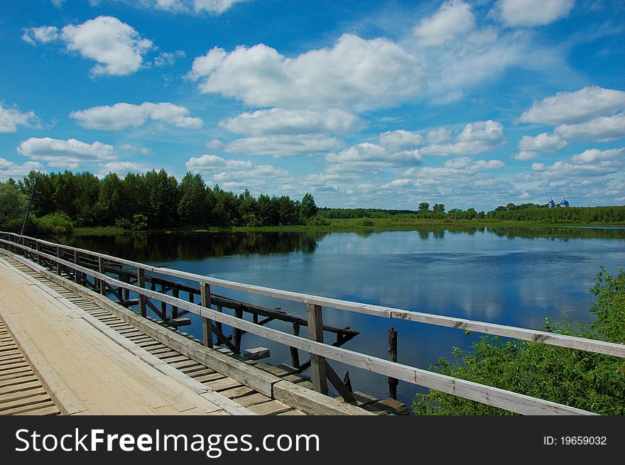 Wooden bridge over the river in sunny summer day