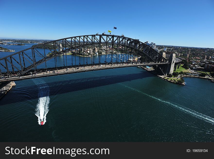 An aerial view of the Sydney Harbour Bridge as the sunlight shimmers on the water below.