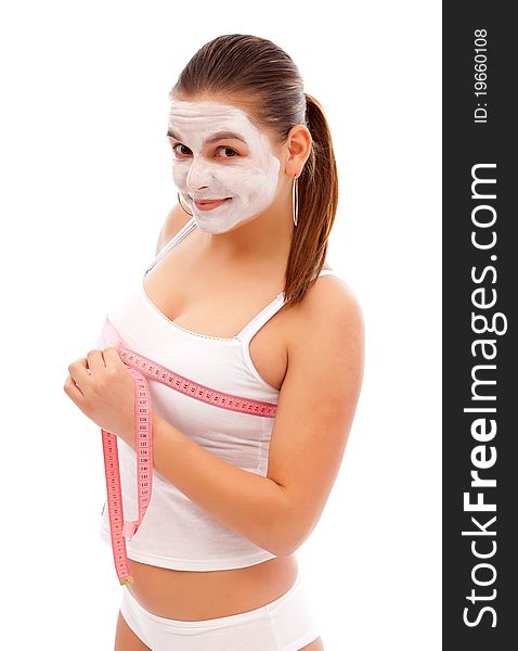 Young woman with a beauty mask measures her breast with a measuring tape. Young woman with a beauty mask measures her breast with a measuring tape
