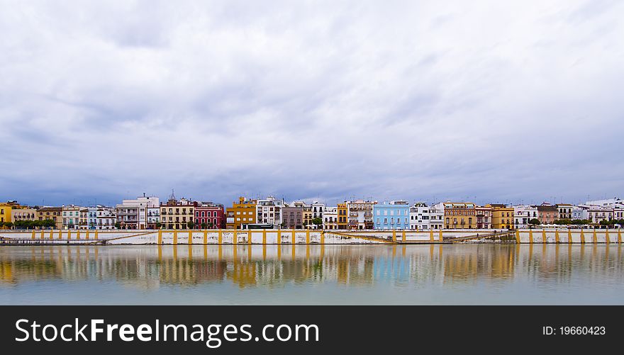 Colorful panorama of Seville riverside on the overcast day, forming amazing pastel colors and reflections in the river. Colorful panorama of Seville riverside on the overcast day, forming amazing pastel colors and reflections in the river.