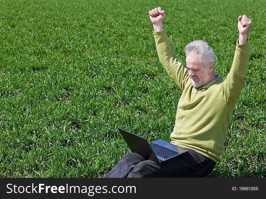 Exciting grandfather with a notebook on a grass. Exciting grandfather with a notebook on a grass