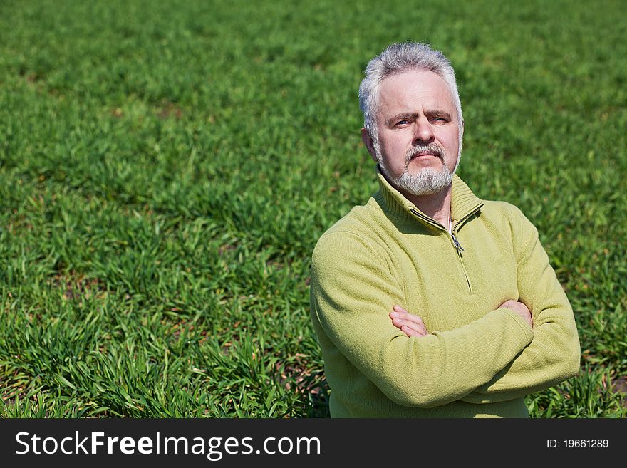 Old man on a green field with hands crossed. Old man on a green field with hands crossed