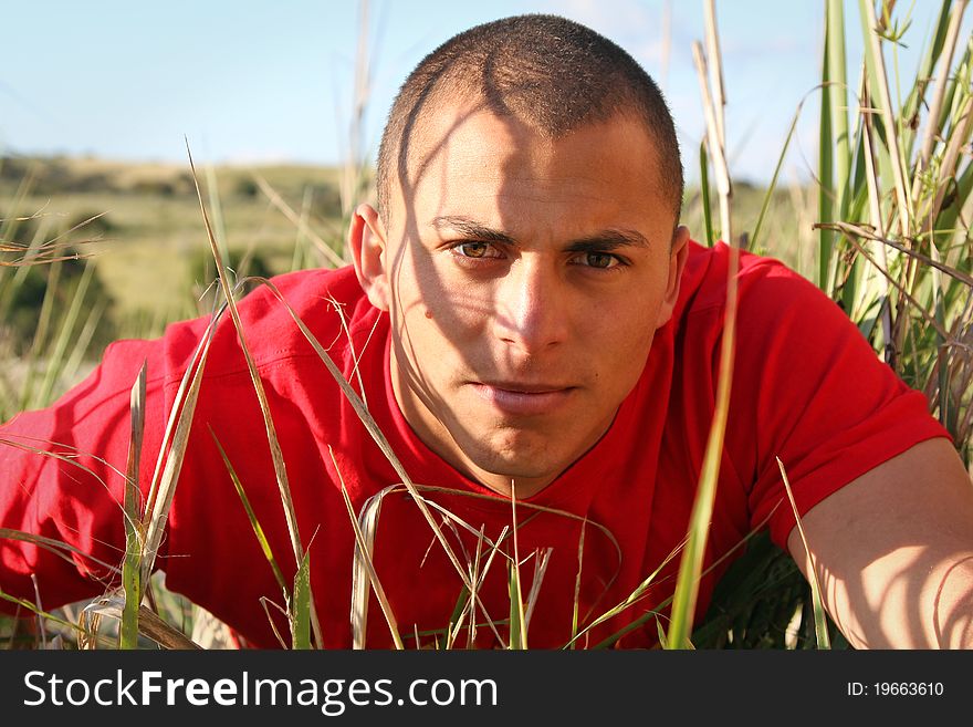 Man with intense look crawling through the grass
