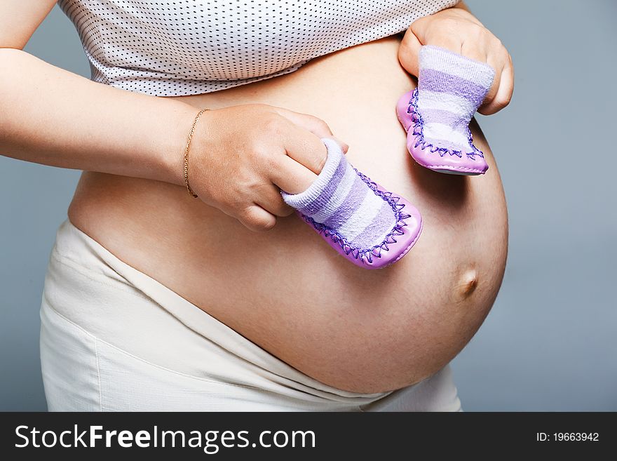 Pregnant Woman Holding Pair Of Shoes