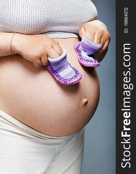 Pregnant woman holding pair of shoes for baby