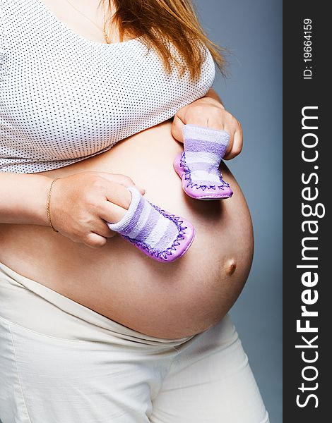 Pregnant woman holding pair of shoes