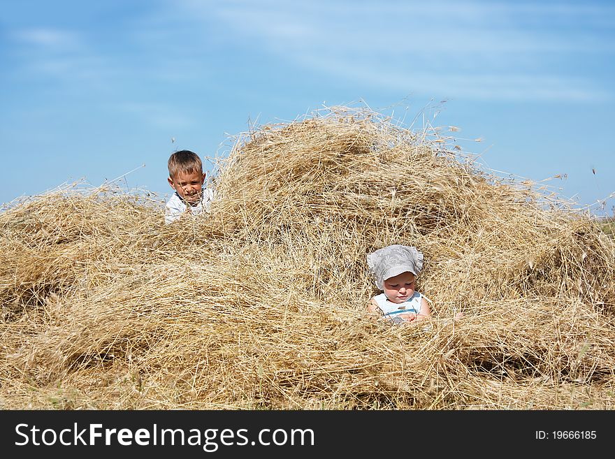 Two children playing in haystack