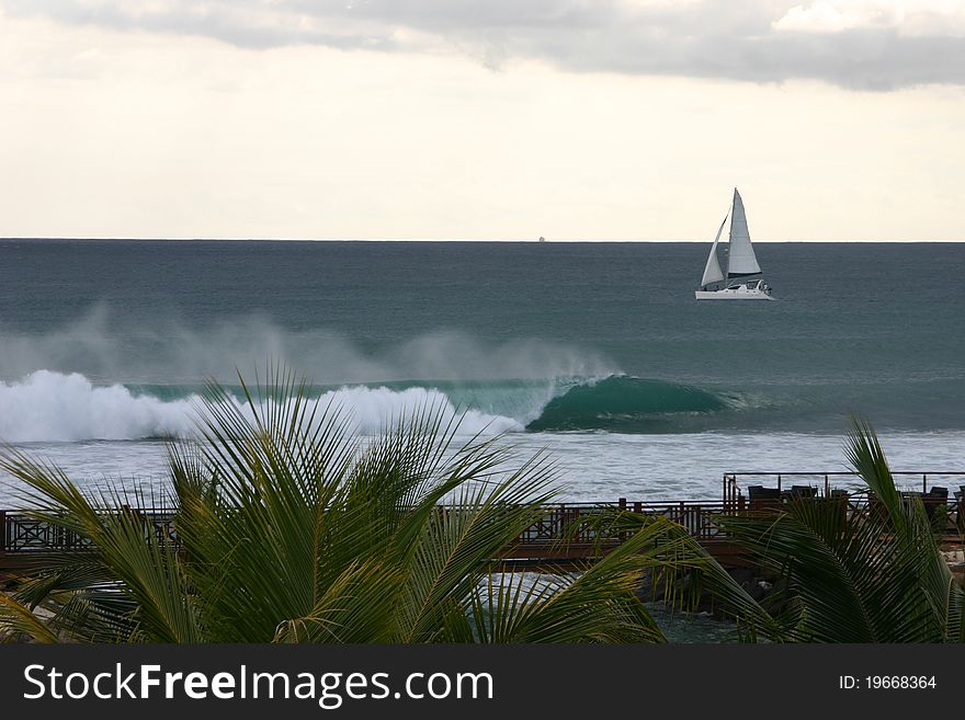 Beach scene with crashing waves and lonely sailboat in Mauritius. Beach scene with crashing waves and lonely sailboat in Mauritius.