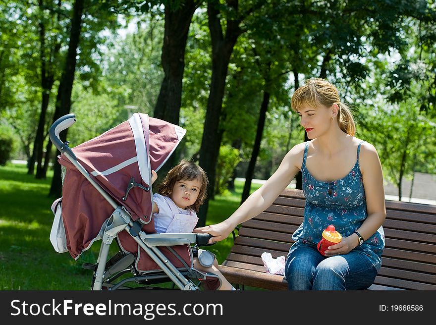 Young woman on bench with a pram in a park