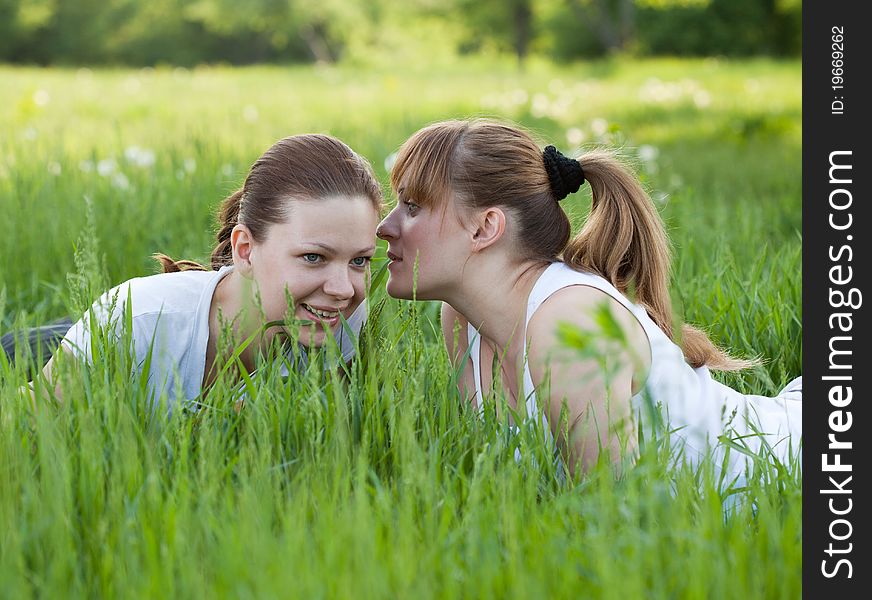 Girls lying in a grass and telling secret to each other. Girls lying in a grass and telling secret to each other