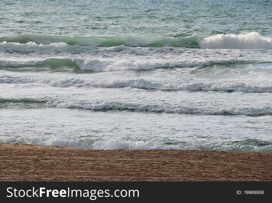 Sea coast with small waves and white horses formed by foam. Sea coast with small waves and white horses formed by foam