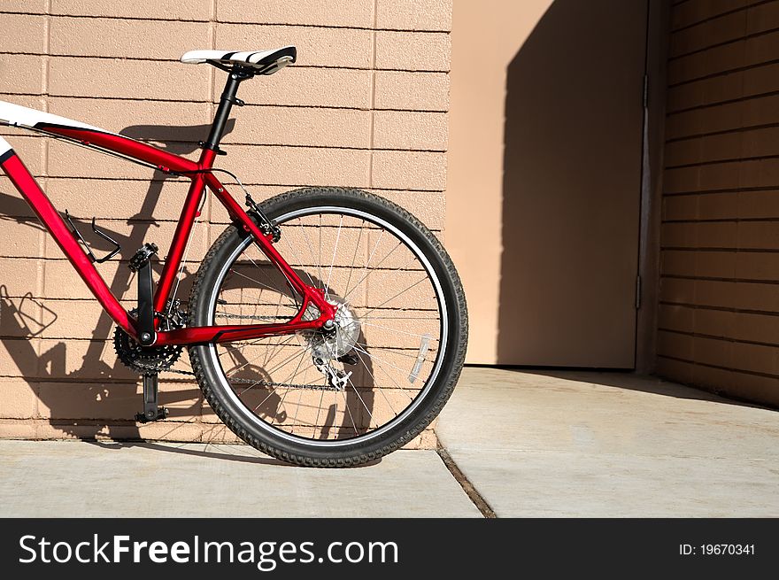 Red bicycle parked next to a wall