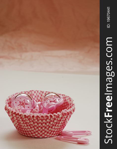 Pink baby rattles in white and red paper cup cake holders. Pink baby rattles in white and red paper cup cake holders