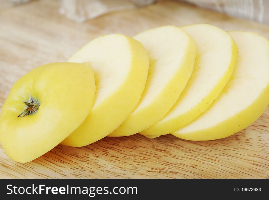 Slices of a yellow juicy apple on a chopping board