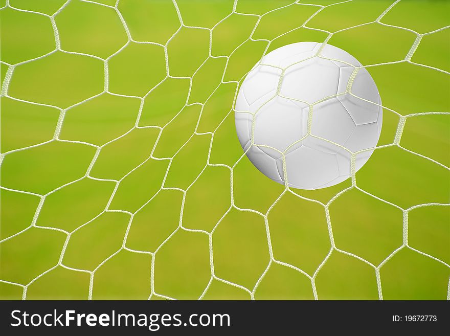 A goal in a soccer match: traditional black and white football hitting the big net in front of blue sky background. A goal in a soccer match: traditional black and white football hitting the big net in front of blue sky background