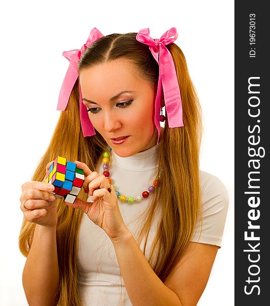 Girl with two tails and pink ribbons considering a toy on a white background. Girl with two tails and pink ribbons considering a toy on a white background