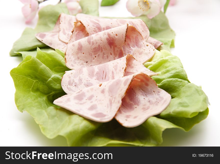 Folded ham sausage and on lettuce leaf