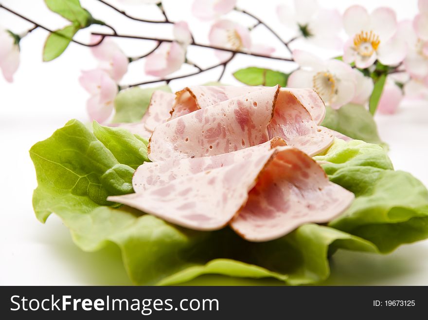 Ham sausage on lettuce leaf with flower