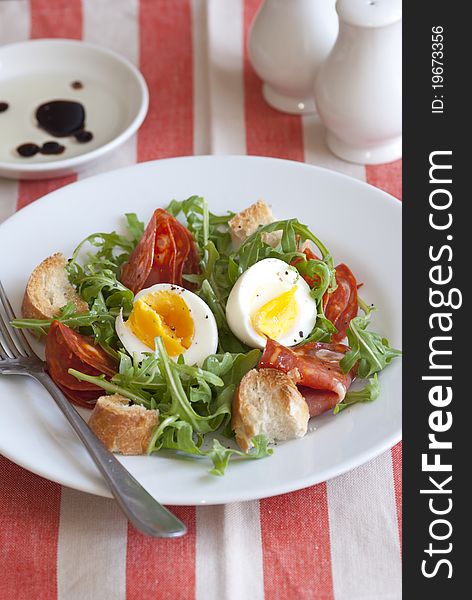 Soft-boiled egg, chorizo and rocket salad on a plate. Soft-boiled egg, chorizo and rocket salad on a plate