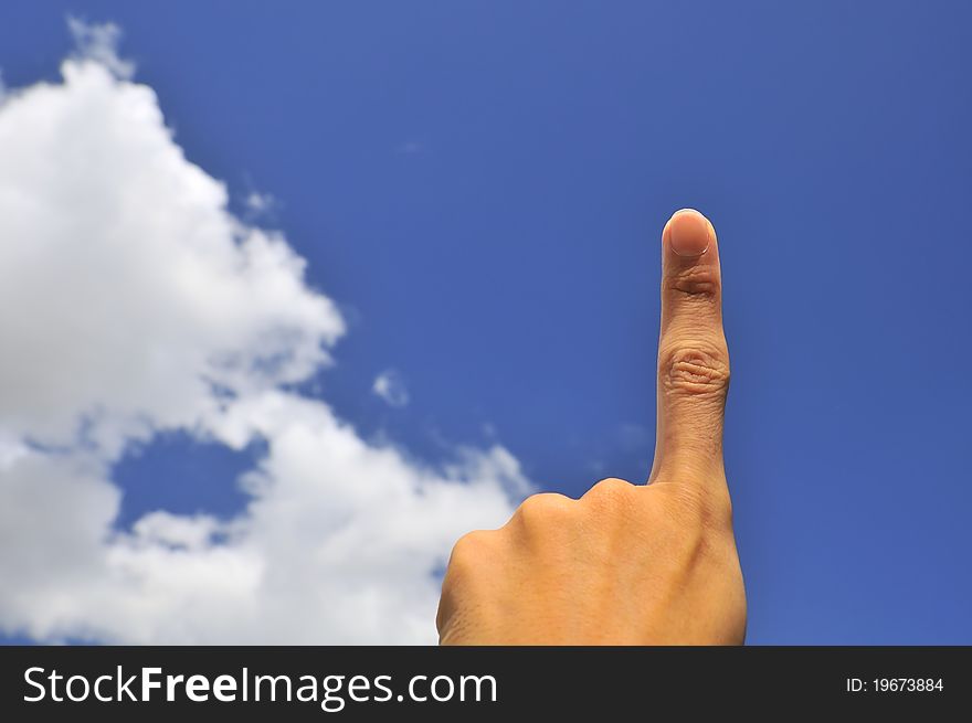 Hand of young male pointing index finger on right of frame with blue sky background. Hand of young male pointing index finger on right of frame with blue sky background.
