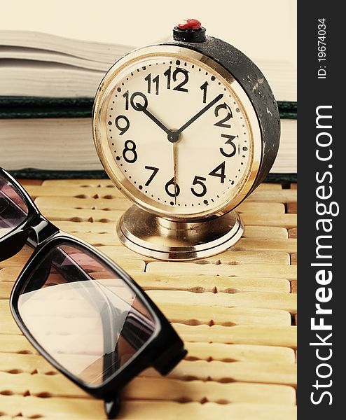 Book with alarm clock and eyeglasses. Book with alarm clock and eyeglasses