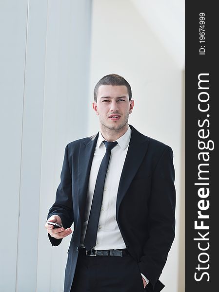 Young business man talk by cellphone over bright window in big hall