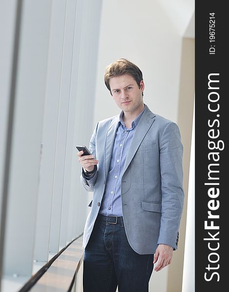 Young business man talk by cellphone over bright window in big hall