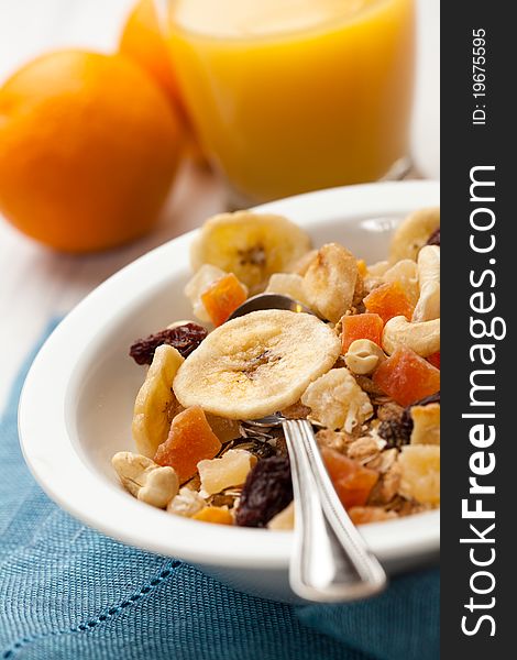 Bowl of muesli and orange juice in background