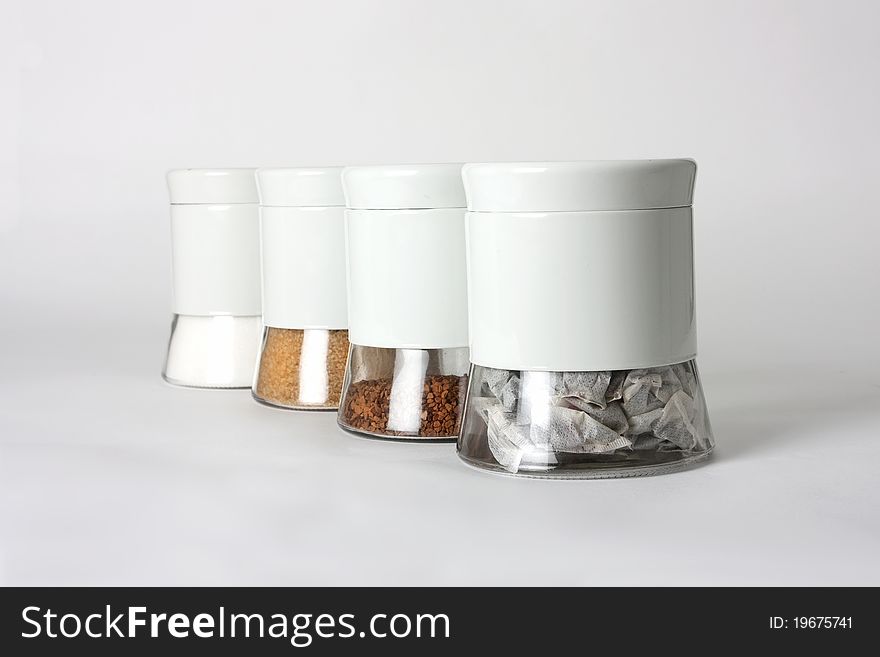 Pots made from glass holding teabags, coffee granules and brown and white sugar. Pots made from glass holding teabags, coffee granules and brown and white sugar