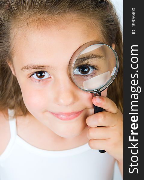 Beautiful little girl looking through a magnifying glass