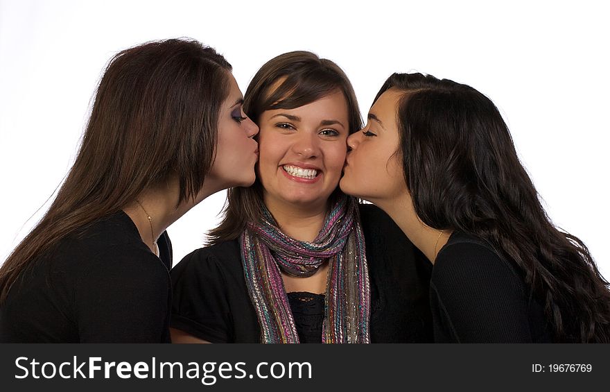 Two younger adult sisters kissing their older sister on the check while the older sister smiles with approval. Two younger adult sisters kissing their older sister on the check while the older sister smiles with approval.