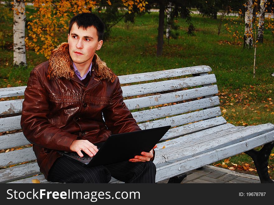 Man with laptop outdoor, in the autumn park. Man with laptop outdoor, in the autumn park.