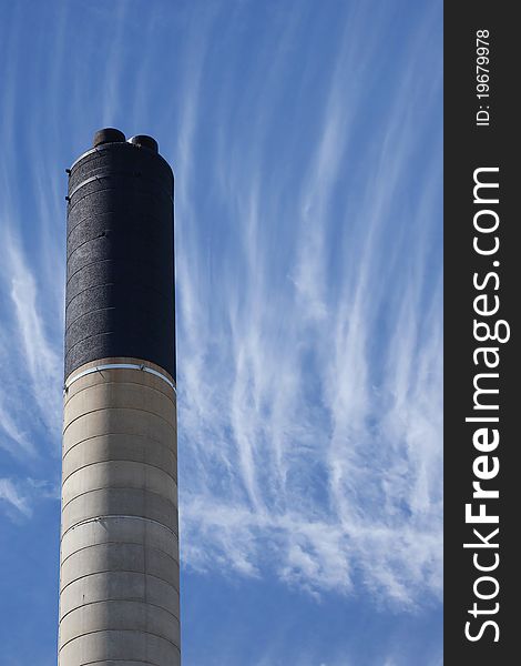 Single concrete industrial chimney and cloudy sky